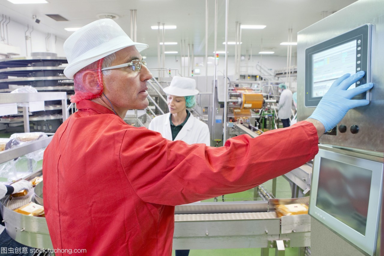 在奶酪加工廠生產線控制面板上的工人